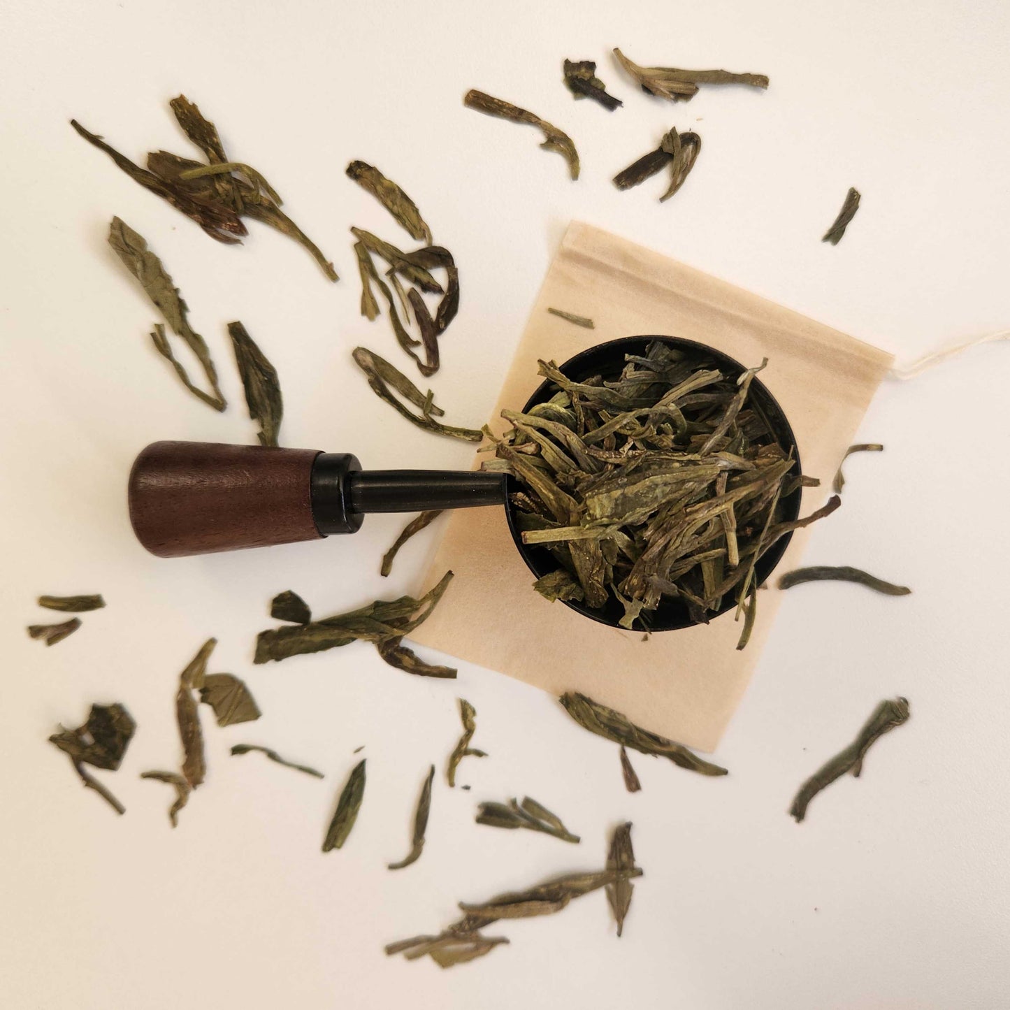 Monimo biodegradable and home compostable eco-friendly teabag pictured with Long Jing green tea leaves.