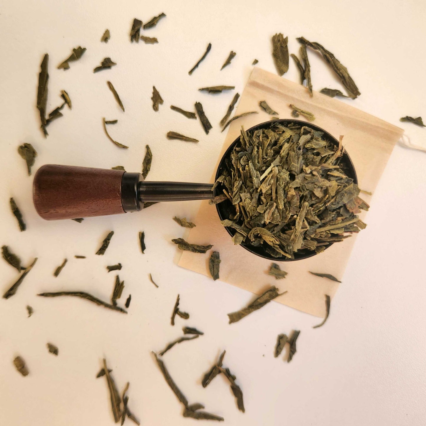 Monimo biodegradable and home compostable eco-friendly teabag pictured with Sencha green tea leaves.